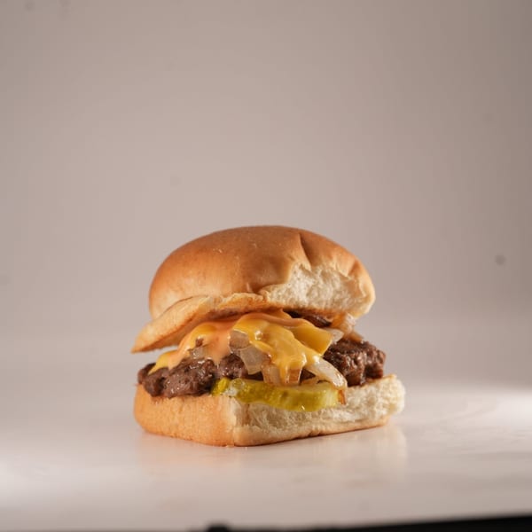 A Burger Truck slider with melted cheese, grilled onions, and pickles on a bun.