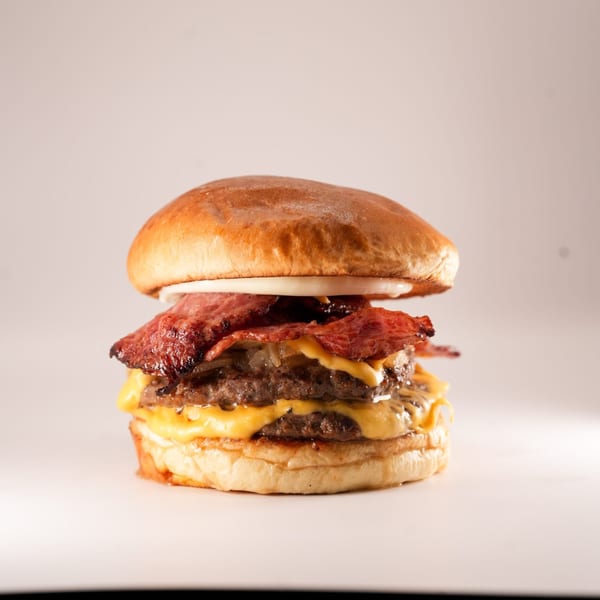 A double patty Burger Truck burger with melted cheese, bacon, and onions on a brioche bun.