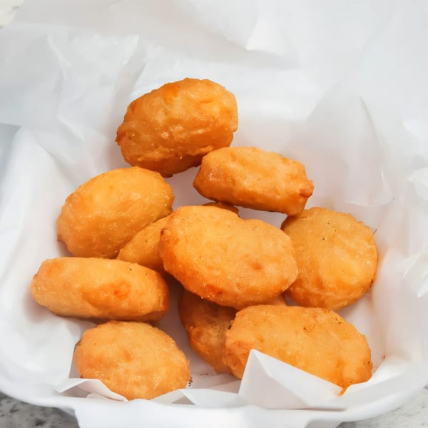 Golden-brown chicken nuggets from The Burger Truck, served in a white paper-lined container.
