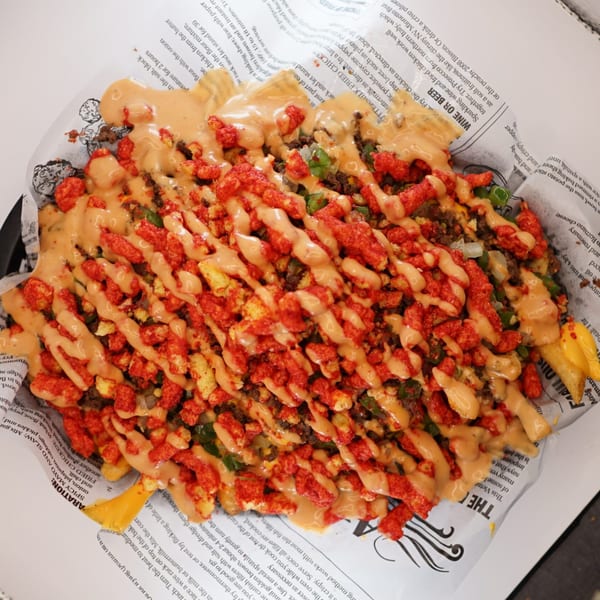 A close-up of The Burger Truck's loaded fries, topped with cheese sauce, ground beef, and Cheetos.