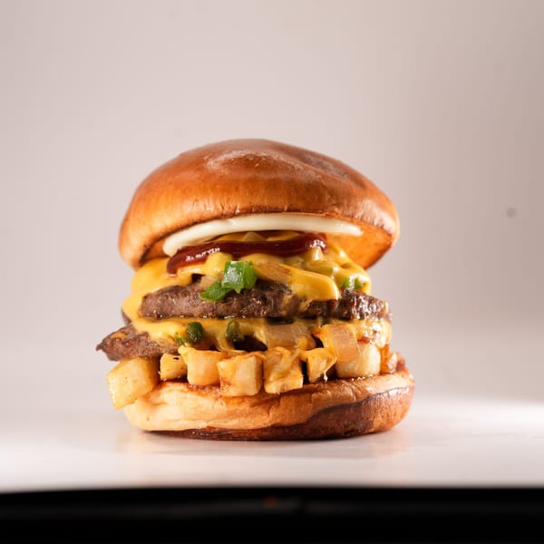 A double cheeseburger from The Burger Truck, topped with fries, onions, and sauces.