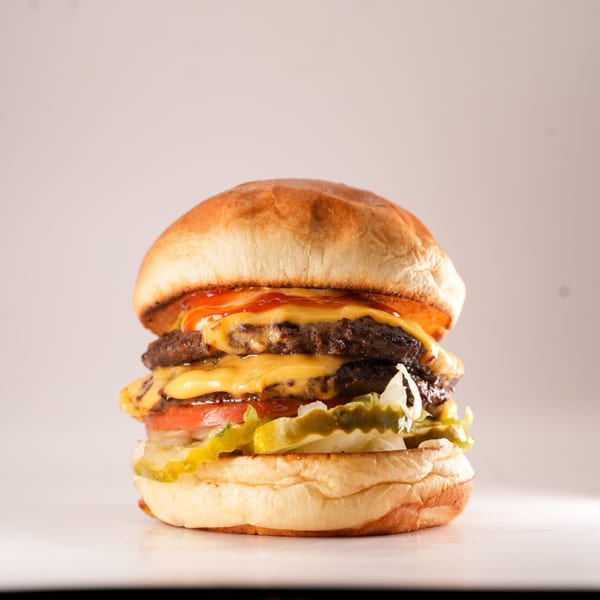 A double cheeseburger from The Burger Truck with ketchup, lettuce, tomato, and pickles.
